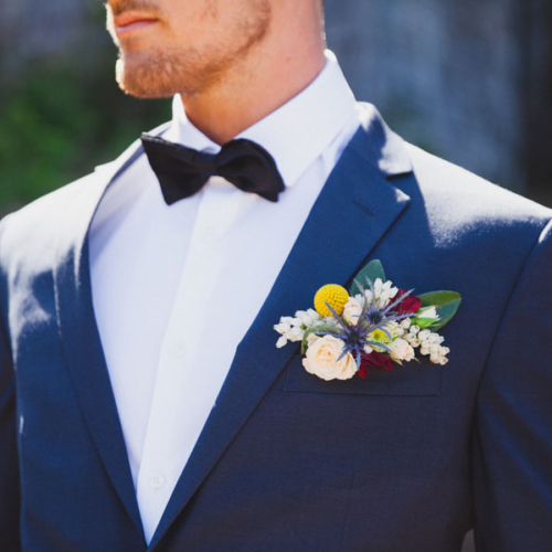 groom with bootineer of yellow, white, red flowers, by Parksville florist Petal and Kettle