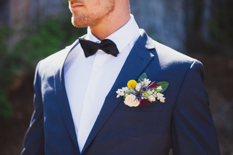 groom with bootineer of yellow, white, red flowers, by Parksville florist Petal and Kettle