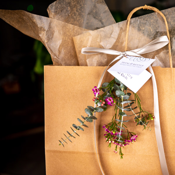 wrapped gift in a paper bag from Petal and Kettle